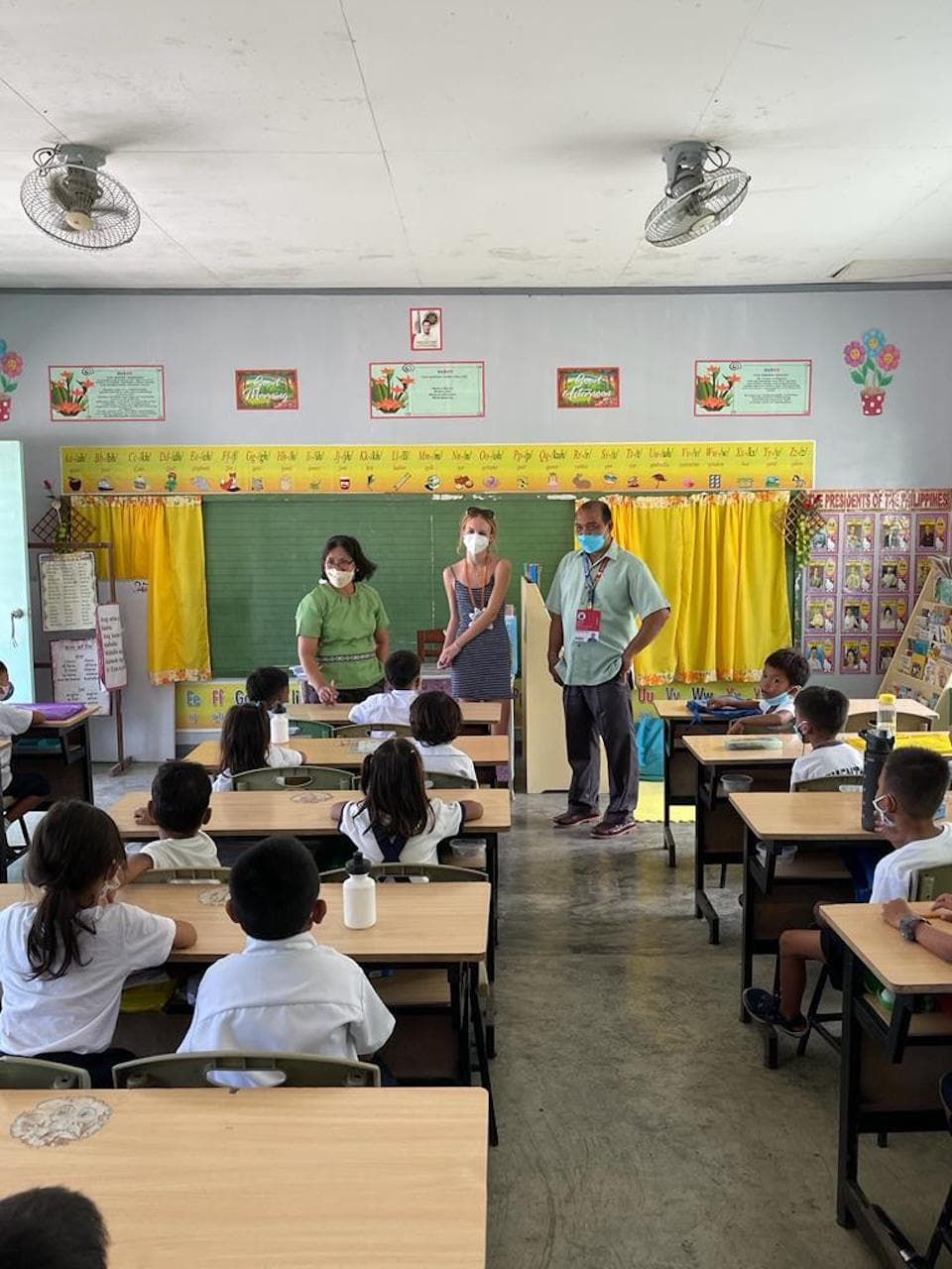 Natalia and teachers standing in front of a classroom full of children