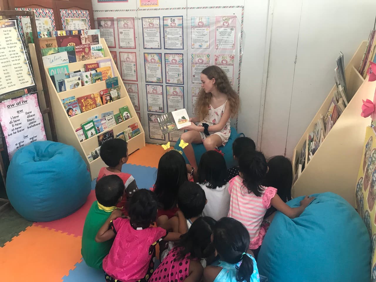 Natalia reading a book to a group of children at a Reading Nook