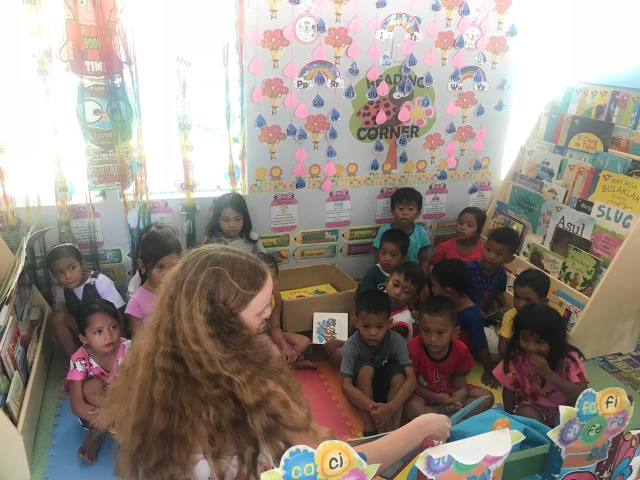 Natalia reading a book to a group of children at a Reading Nook