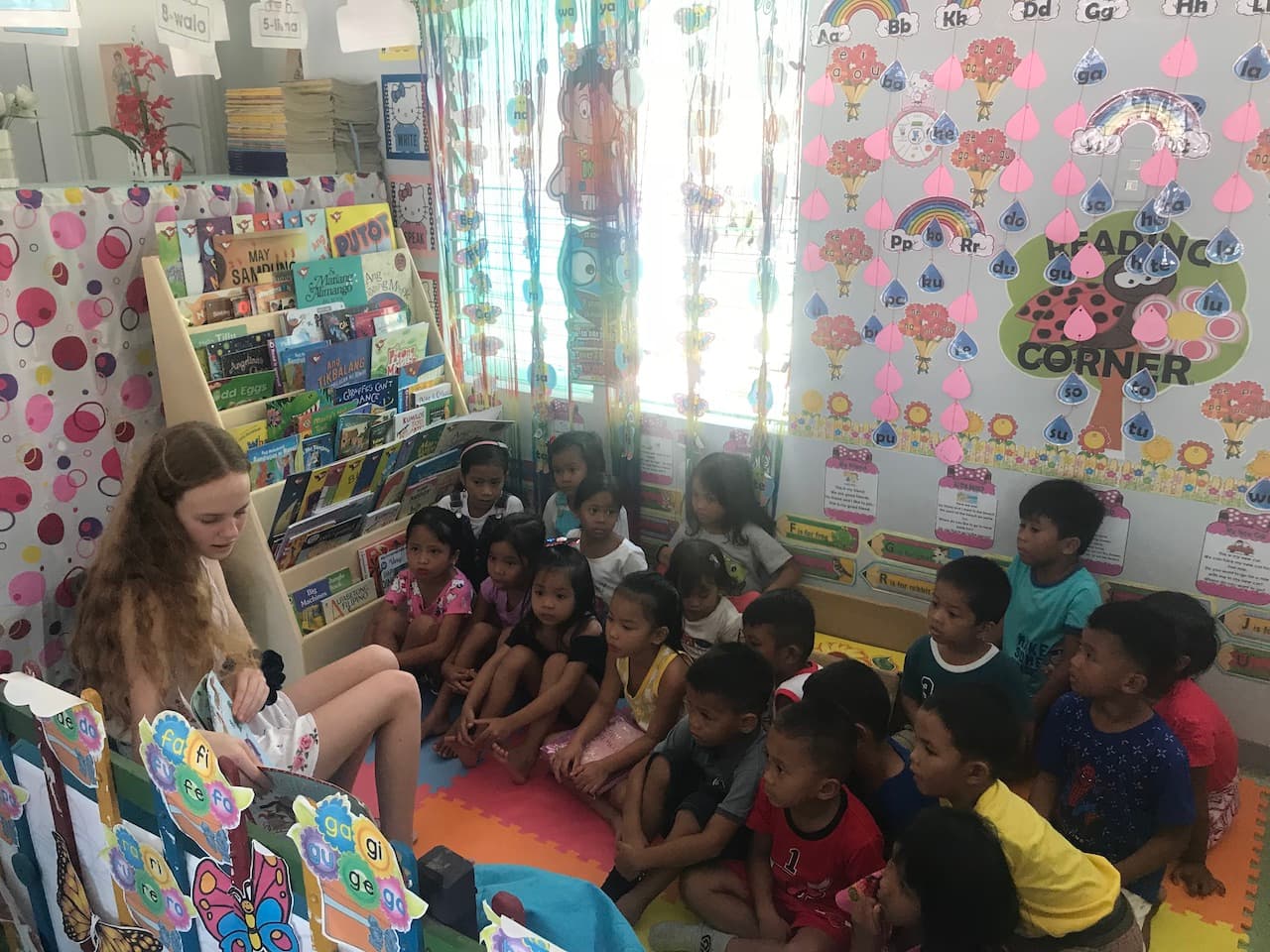 Natalia reading a book to a group of children at a Reading Nook